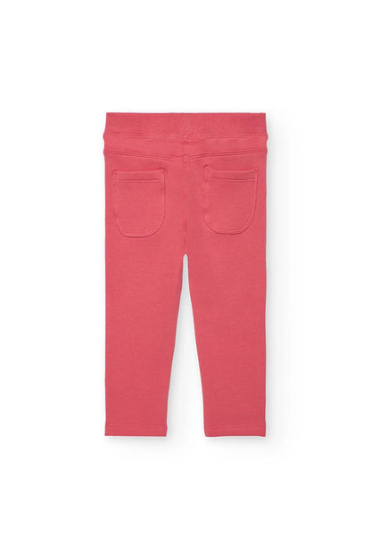 Vista trasera de los jeggings de felpa color coral, mostrando los bolsillos de parche.