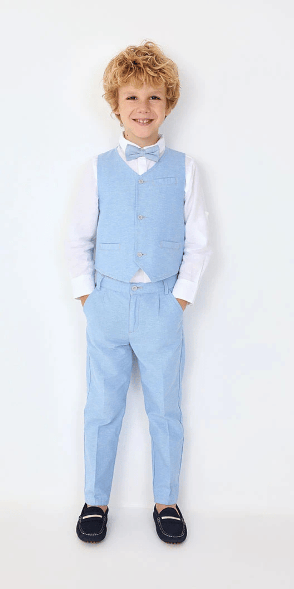 Niño usando conjunto formal de Boboli con camisa blanca, pantalón azul, chaleco azul y moño.