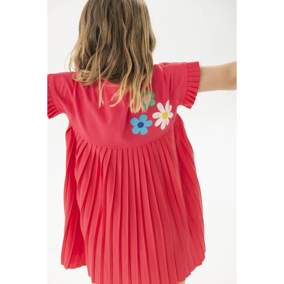 Niña mostrando la parte trasera del vestido rojo Boboli con diseño de flores y falda plisada.