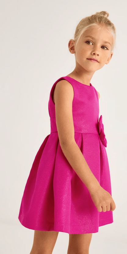 Modelo infantil luciendo un vestido magenta fiusha de Mayoral, con corte fluido y detalles sofisticados.