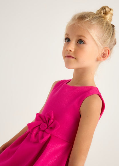 Modelo infantil luciendo un vestido magenta fiusha de Mayoral, con corte fluido y detalles sofisticados.