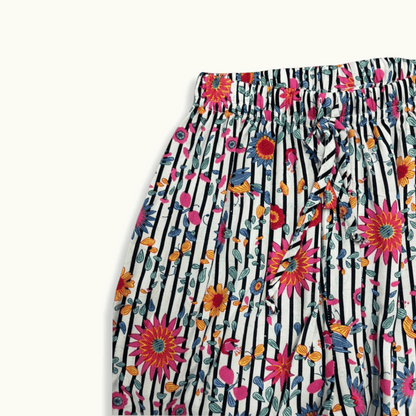 Detalle del pantalón infantil con estampado tropical de flores y rayas, resorte en la cintura y lazo ajustable para mayor comodidad y estilo vibrante.