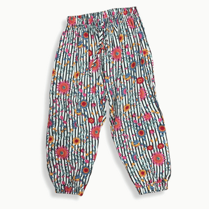 Pantalón infantil con estampado vibrante de flores y rayas, confeccionado en tela ligera con cintura elástica y resorte en los tobillos para mayor comodidad.