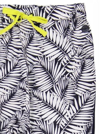 Detalle del pantalón estampado con hojas negras y blancas, con moño amarillo neón y botón decorativo.
