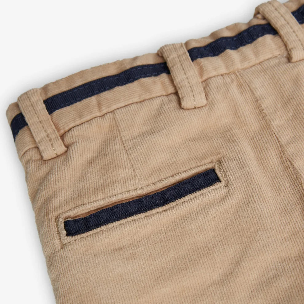 Detalle de bolsillo trasero y cinturilla del pantalón beige de pana para niño.