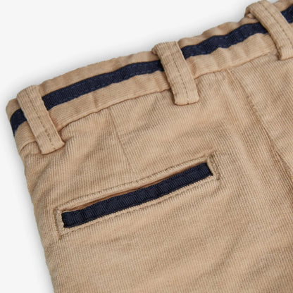 Detalle de bolsillo trasero y cinturilla del pantalón beige de pana para niño.