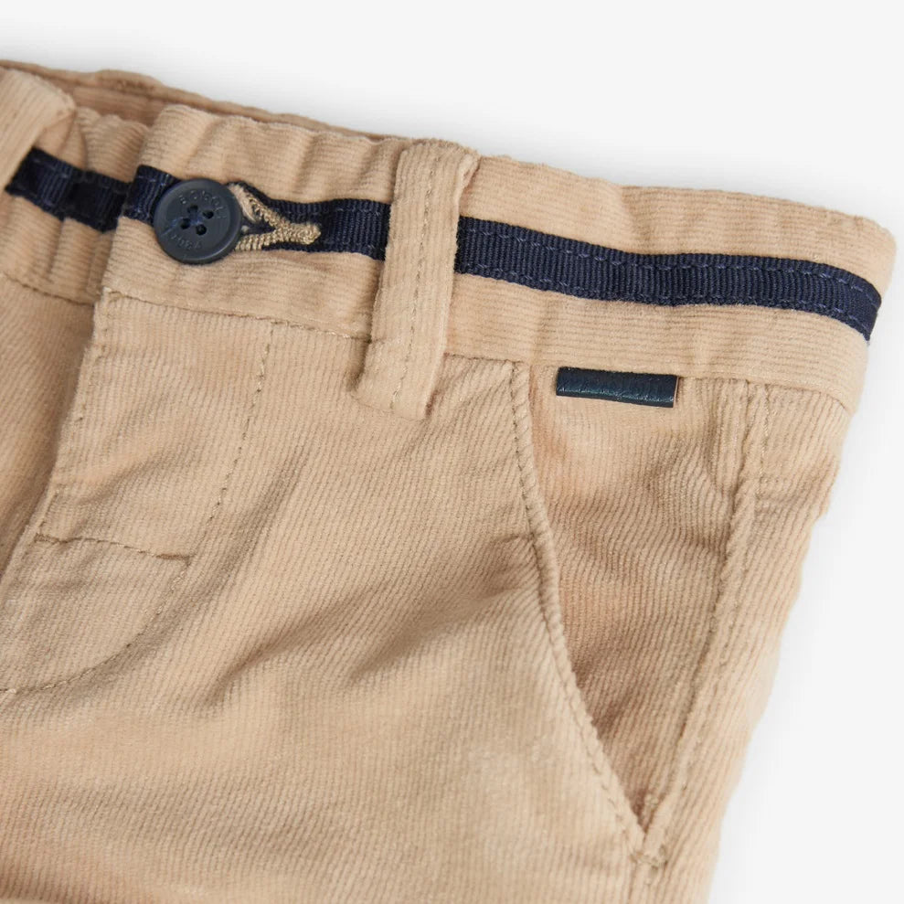 Detalle del frente del pantalón beige de pana para niño con botón azul marino