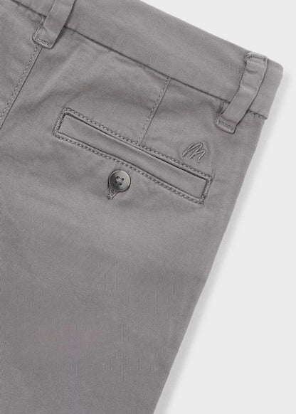 Detalle del bolsillo trasero con botón y el logo bordado de un pantalón chino gris, marca Mayoral.