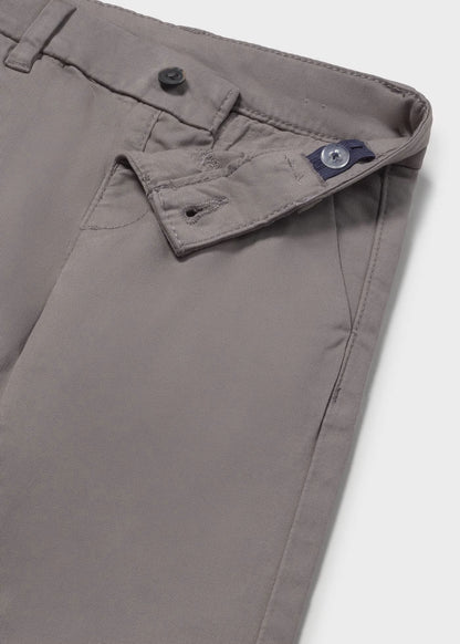Detalle del botón y la cintura interior ajustable de un pantalón chino gris para niño.