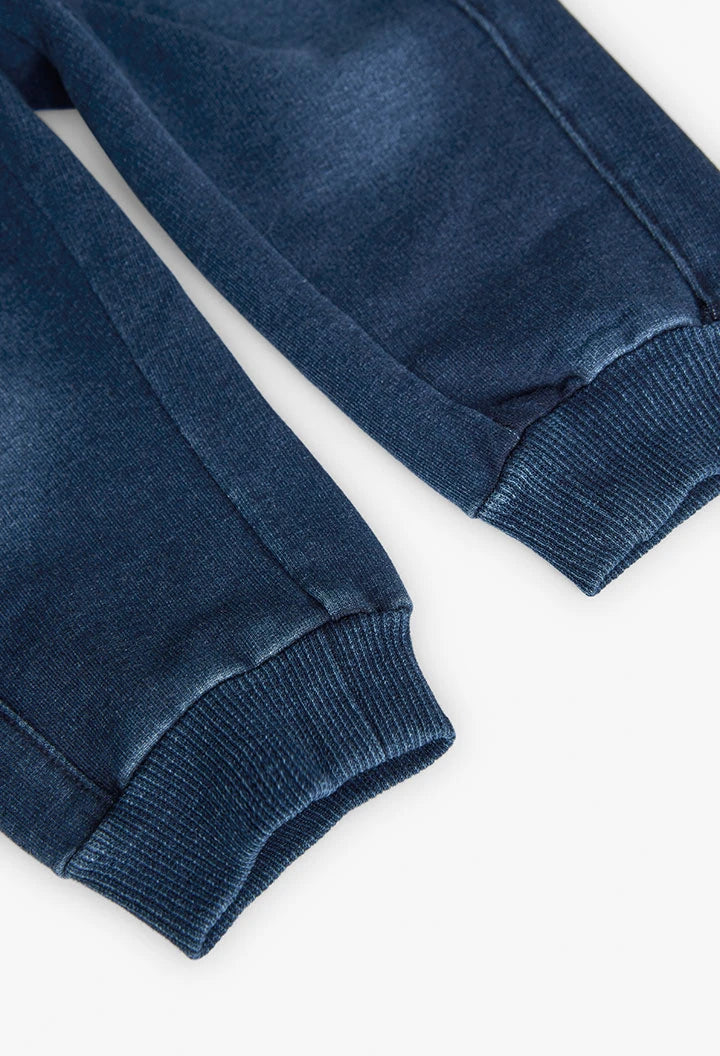 Detalle inferior de pants azul marino tipo jogger con puños acanalados en los tobillos.