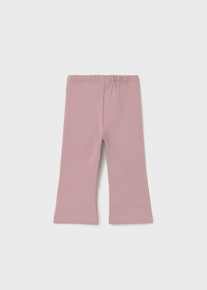 Vista frontal de un pantalón de licra color rosa malva para niña con corte acampanado y cintura elástica.