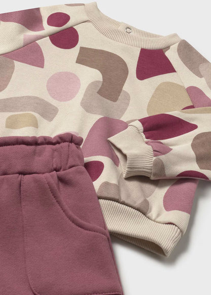 Detalle de un conjunto de felpa, mostrando el estampado de la sudadera, el puño y la cintura elástica del pantalón.