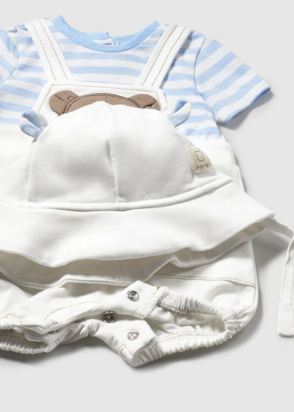 Detalle del conjunto para bebé que incluye un enterizo blanco con broches a presión para facilitar el cambio de pañal, una camiseta de rayas azul y blanca y un gorro con orejitas. El diseño presenta un tierno bordado de osito, ideal para un look adorable y cómodo.