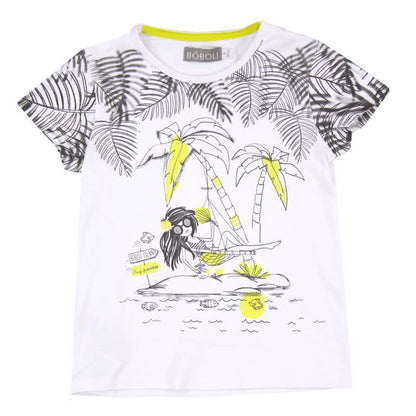 Playera blanca para niña con diseño tropical, palmeras y niña en hamaca, acentos amarillos.