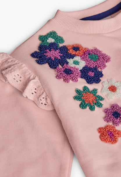 Primer plano de las flores bordadas con textura y el olán con bordado suizo en una sudadera rosa, marca Boboli.