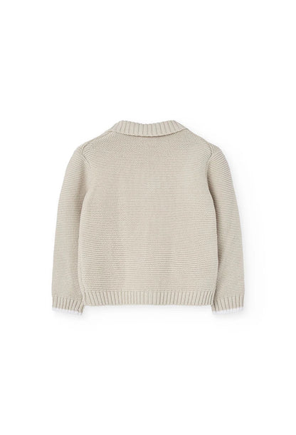 Vista trasera de un suéter beige tejido para niños, con un diseño clásico y cuello tipo chal.