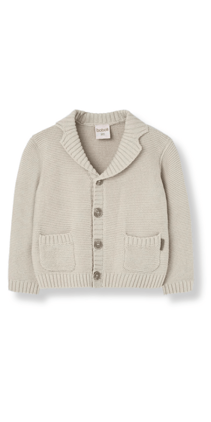 Suéter beige tejido de manga larga para niños, con cuello chal y botones frontales.