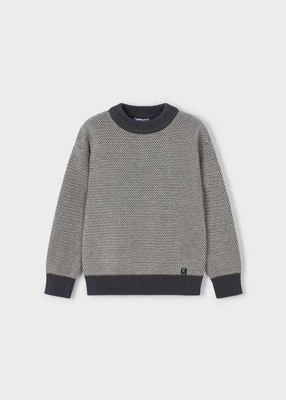 Vista frontal de un suéter de punto para niño, con textura bicolor en gris claro y oscuro, y detalles a contraste, marca Mayoral.