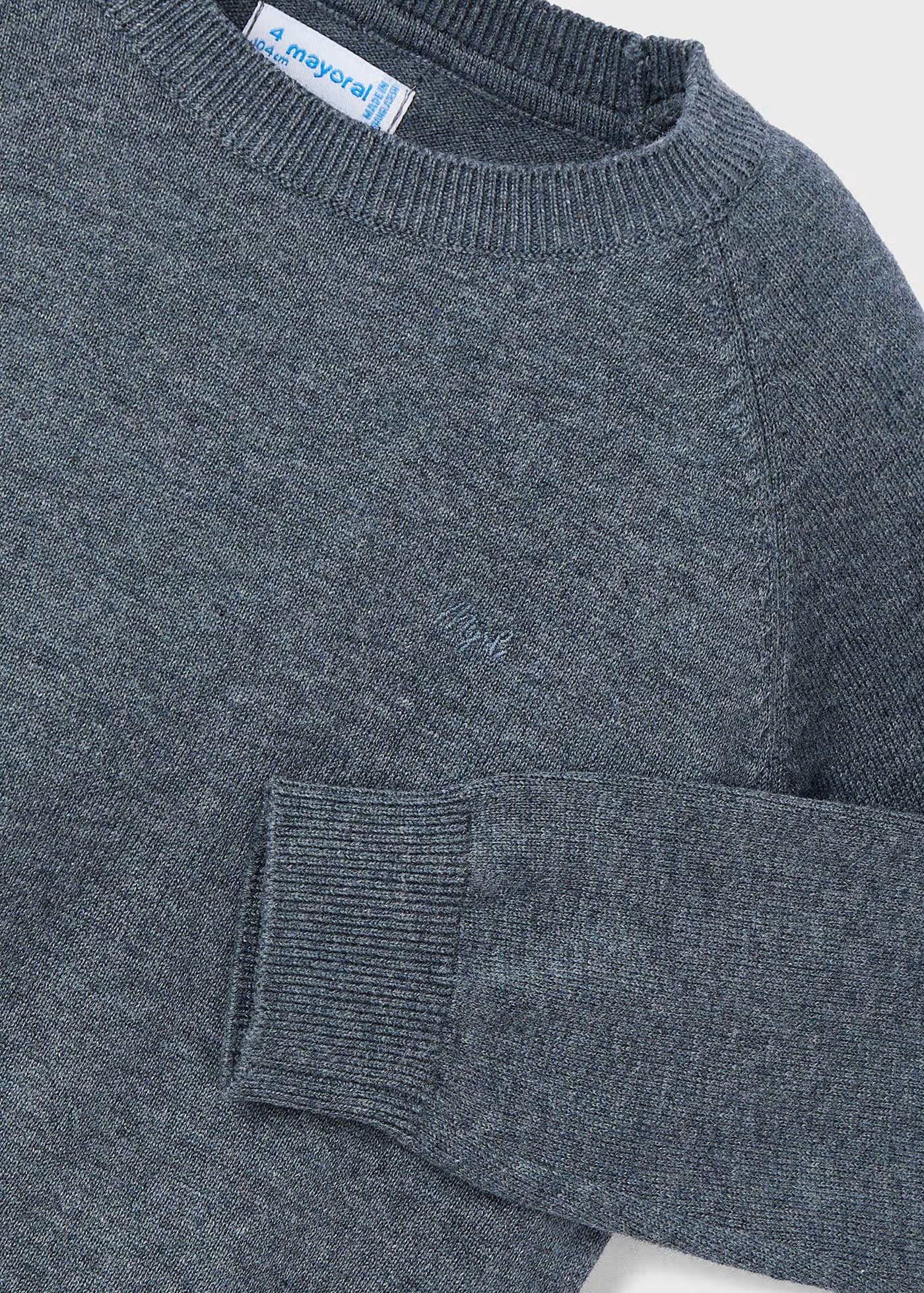 Detalle del cuello, hombro y puño de un suéter gris de tricot Mayoral, mostrando la textura del tejido y el logotipo bordado en el pecho.
