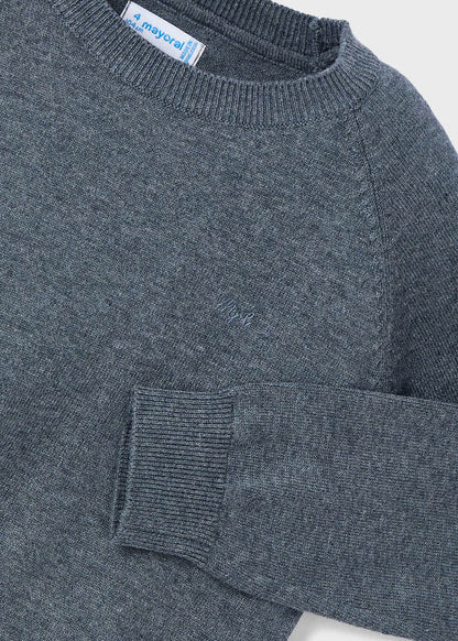 Detalle del cuello, hombro y puño de un suéter gris de tricot Mayoral, mostrando la textura del tejido y el logotipo bordado en el pecho.