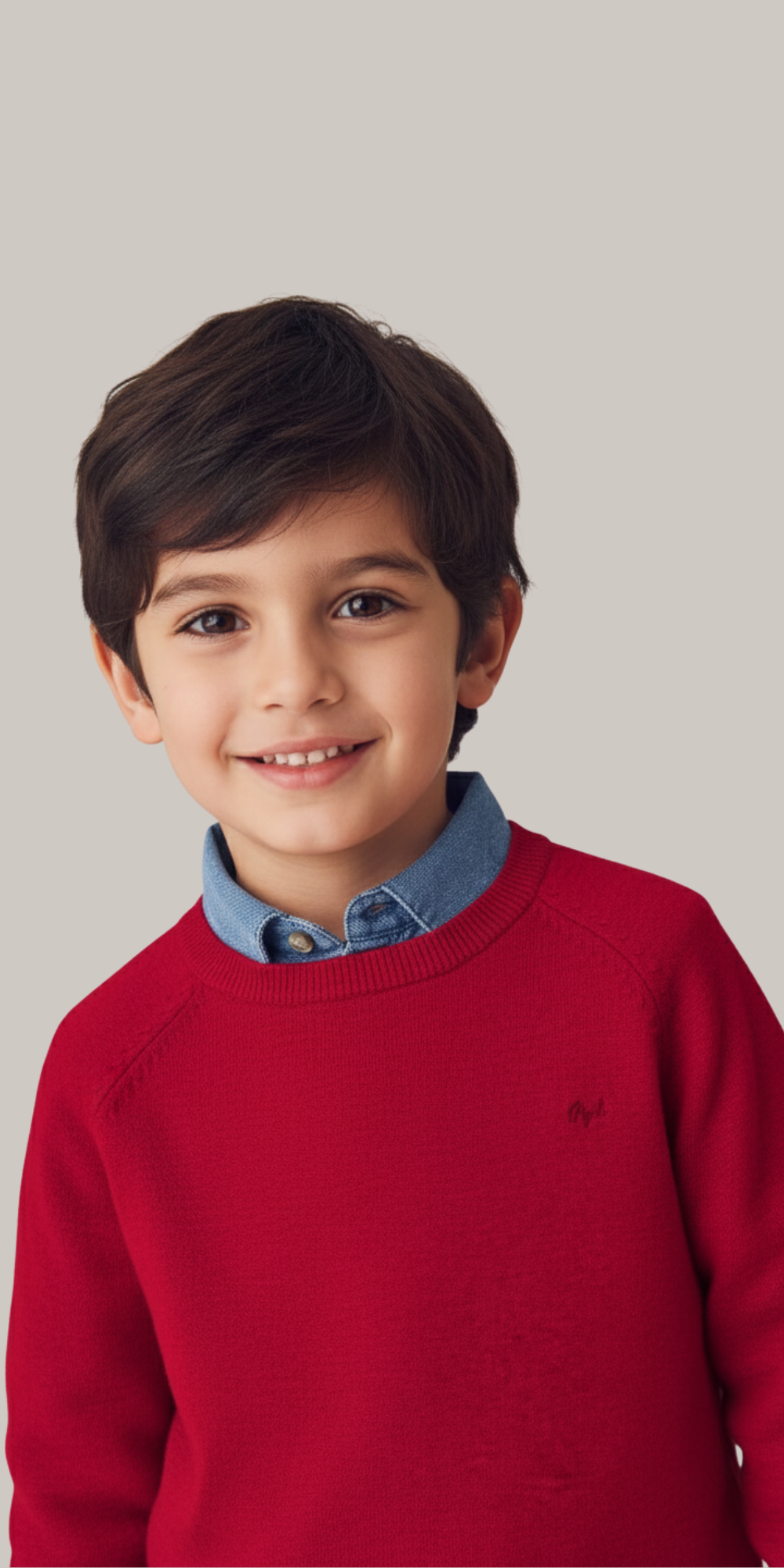 Niño vistiendo el suéter rojo Mayoral sobre una camisa de mezclilla azul.