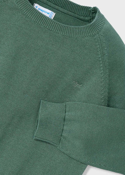 Detalle del cuello, hombro y puño de un suéter verde de tricot Mayoral, mostrando la textura del tejido y el logotipo bordado en el pecho.