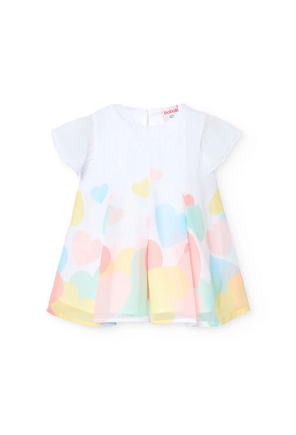 Detalle de la parte inferior de un vestido blanco con estampado de corazones en tonos pastel, mostrando la caída del tejido.