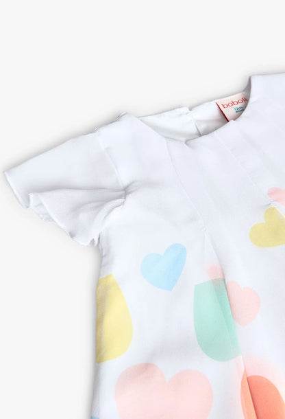 Primer plano de la parte superior de un vestido blanco con estampado de corazones, resaltando los detalles de la tela y el cuello.
