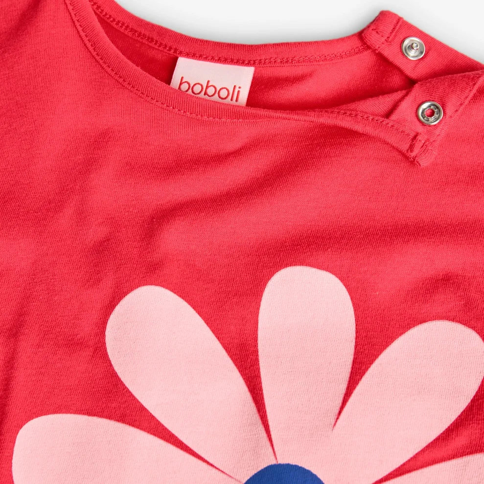 Detalle del cuello redondo con broches y flor rosa del vestido Boboli.