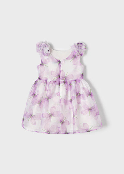 Vista trasera de un vestido infantil con estampado de mariposas en tonos lila y flores decorativas en los hombros, ideal para ocasiones especiales y eventos formales.