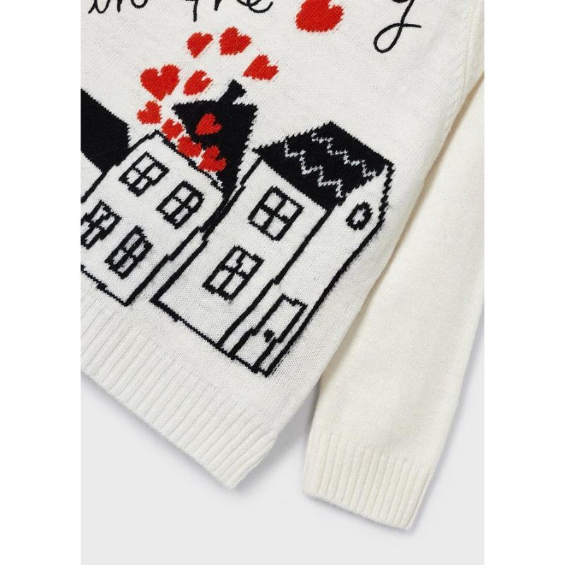 Detalle del tejido del vestido Mayoral con casas y corazones rojos sobre fondo blanco.