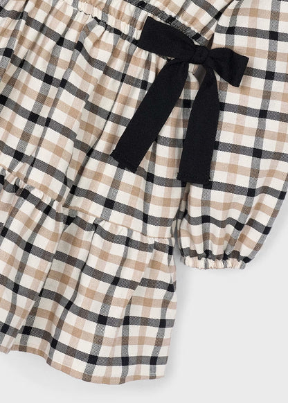Detalle de uno de los moños negros y el volante en la falda de un vestido de sarga a cuadros, marca Mayoral.