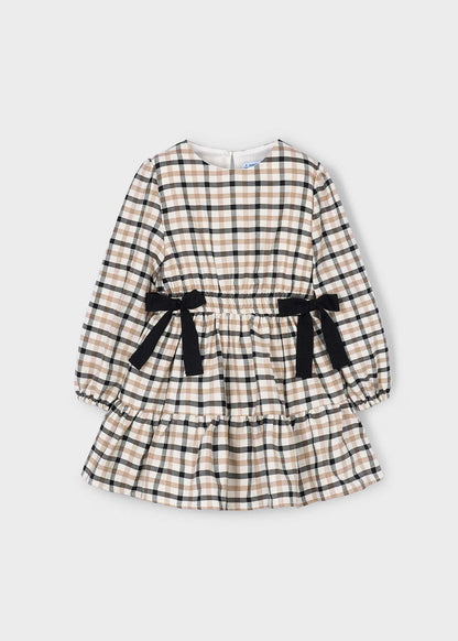 Vista frontal de un vestido de manga larga para niña con estampado de cuadros, cintura elástica, dos moños negros y falda con volante, marca Mayoral.