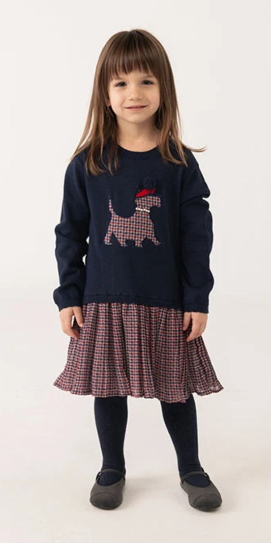 Niña sonriendo usando un vestido azul marino con falda de pata de gallo y un aplique de perro en el pecho, marca Boboli.