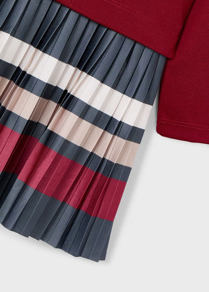 Detalle de la falda plisada de un vestido, mostrando las rayas horizontales en colores gris, vino, crudo y beige.