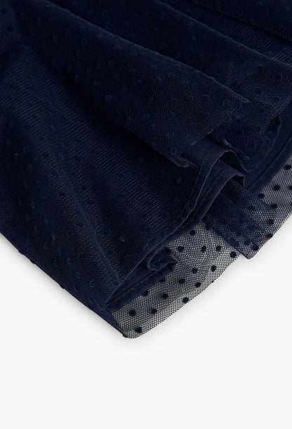 Primer plano de la falda de tul azul marino con estampado de puntos (plumetis) de un vestido para niña.